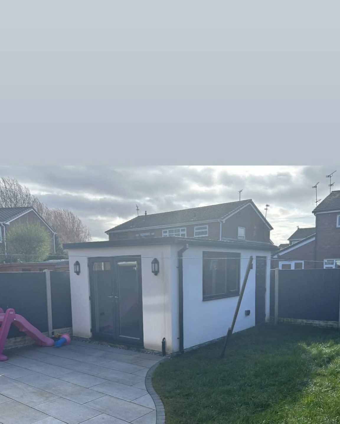 Small rendered outbuilding with a grey door in a back garden