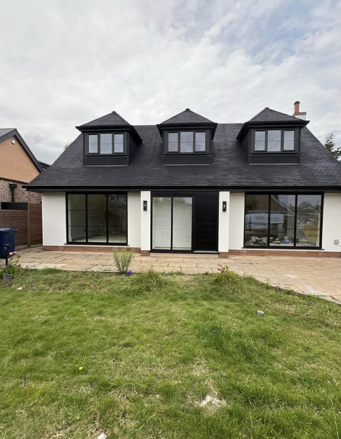 Back of a house in white render with three dormers and wide glazed doors