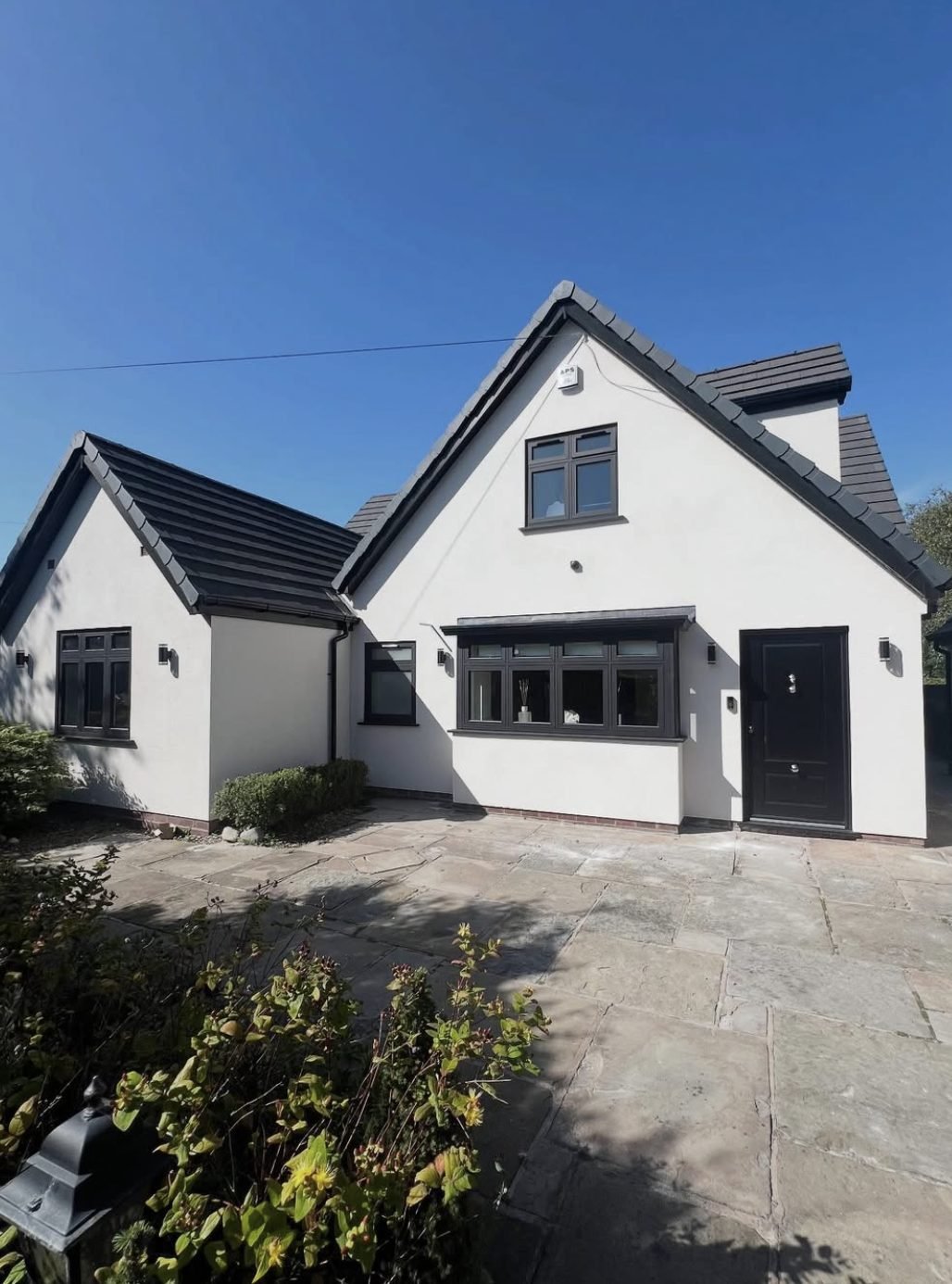 House with steep gables in white render and dark window frames