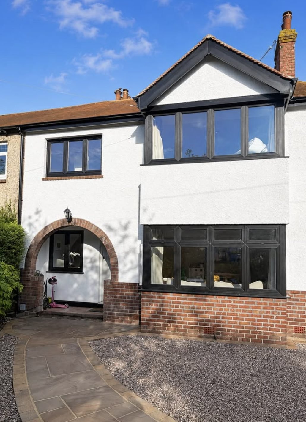 Terraced house in white render with a brick arch over the porch and a brick plinth